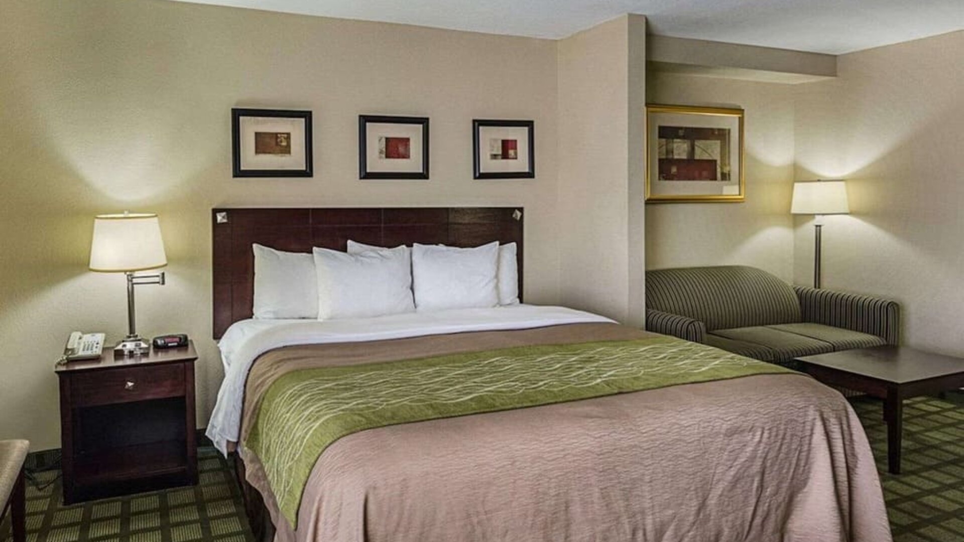 Spacious guest room featuring a king bed, sofa seating area, bedside lighting, and framed artwork at Comfort Inn Southwest At Westpark.