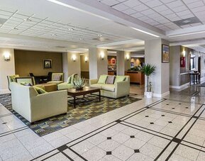 Spacious hotel lobby featuring sofas, armchairs, coffee tables, decorative plants, and tiled flooring at Comfort Inn Southwest At Westpark.
