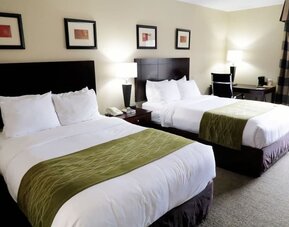 Guest room featuring two beds, bedside lighting, a work desk, chair, and large window at Comfort Inn Southwest At Westpark.