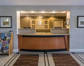 Reception area featuring a front desk, hotel signage, framed artwork, and guest information displays at Comfort Inn Southwest At Westpark.