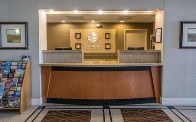 Reception area featuring a front desk, hotel signage, framed artwork, and guest information displays at Comfort Inn Southwest At Westpark.