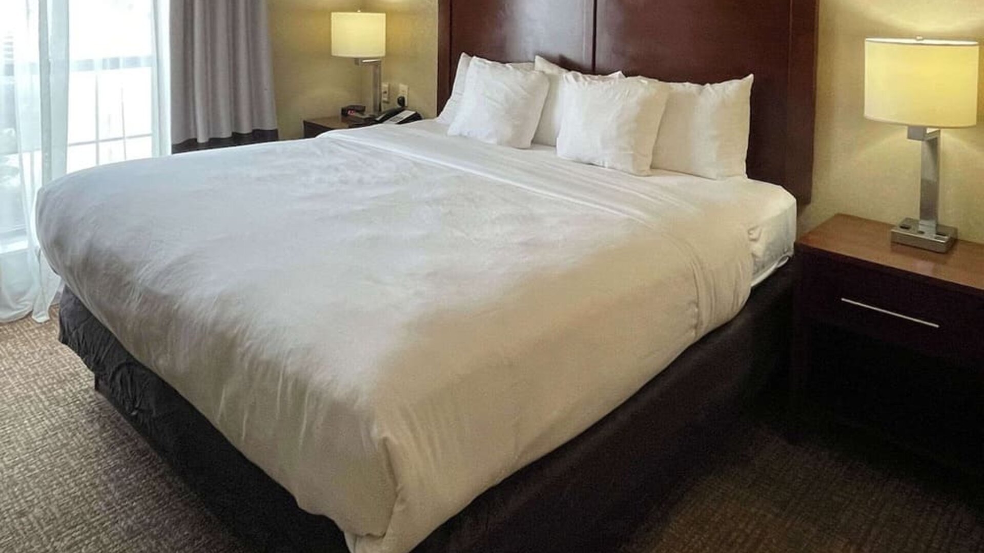 King guest room with a large bed, white bedding, bedside tables, and lamps at Comfort Suites San Antonio SeaWorld - Lackland AFB.