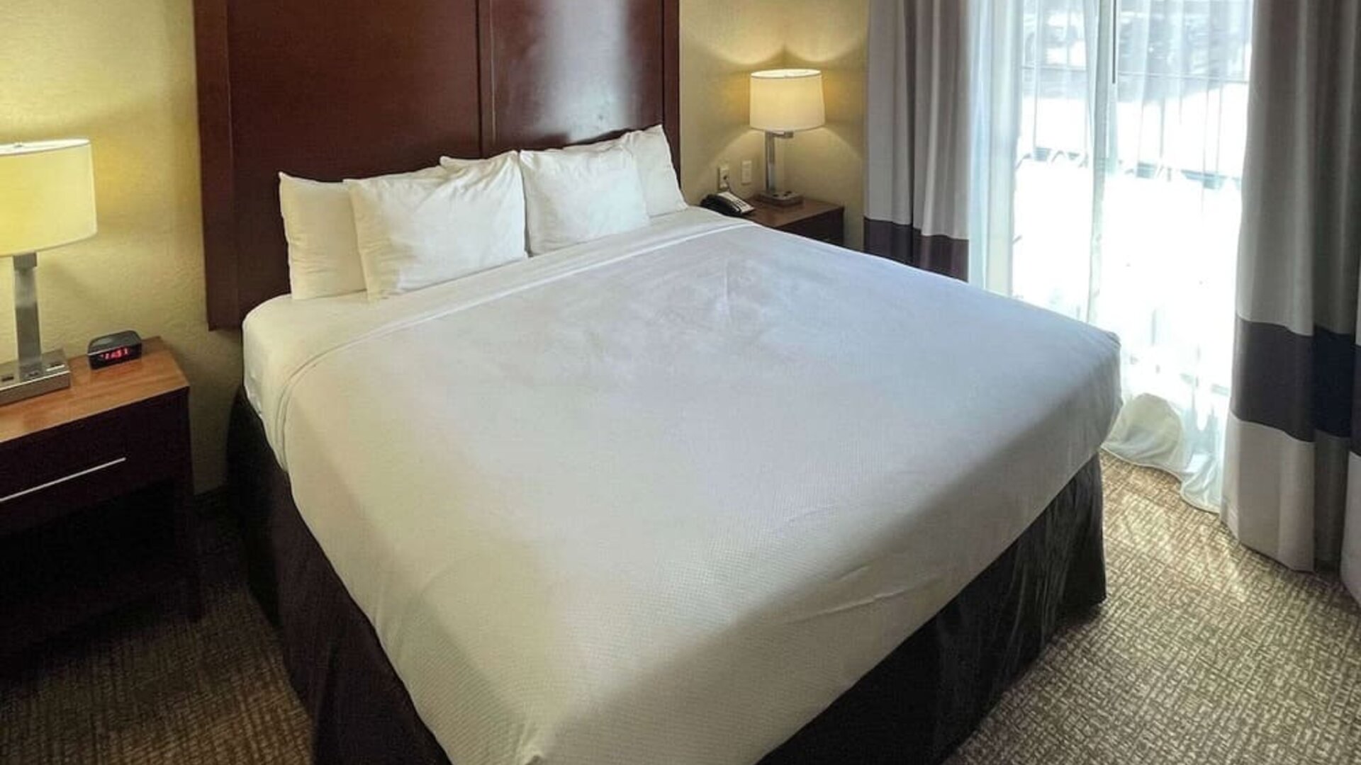 King guest room with a large bed, bedside tables, lamps, and natural light from the window at Comfort Suites San Antonio SeaWorld - Lackland AFB.