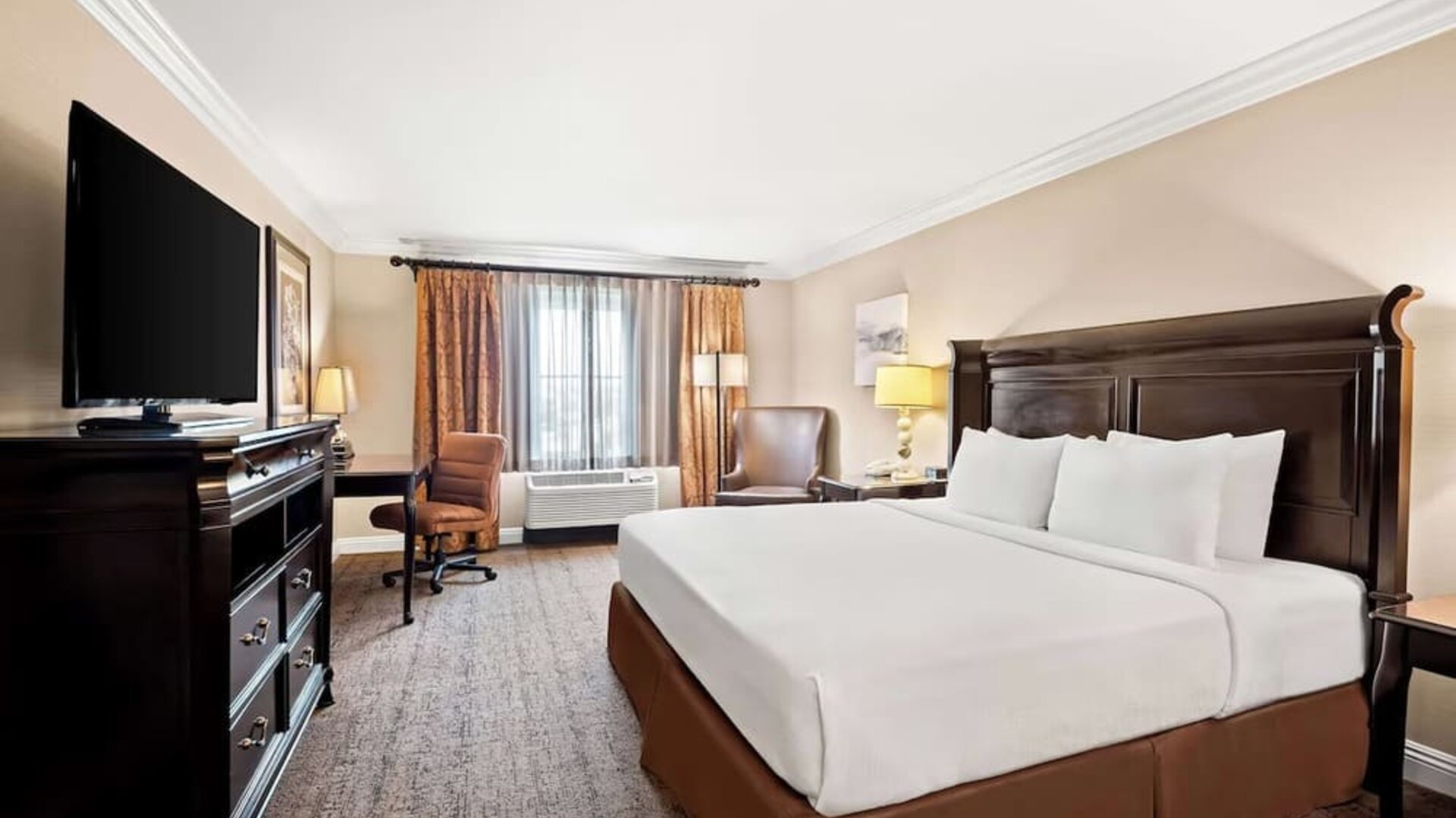 King guest room with white bedding, dark wood furnishings, television, desk, and seating area at Best Western Ontario Mills Mall.