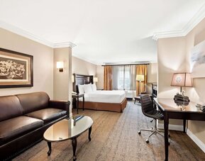 Spacious guest room with king bed, sofa, coffee table, work desk, and seating area at Best Western Ontario Mills Mall.
