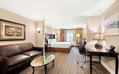 Spacious guest room with king bed, sofa, coffee table, work desk, and seating area at Best Western Ontario Mills Mall.