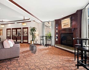 Lobby lounge with sofa seating, fireplace, high-top tables, and large windows at Best Western Ontario Mills Mall.