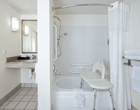 Accessible bathroom with bathtub, shower seat, grab bars, vanity, and mirror at Best Western Ontario Mills Mall.