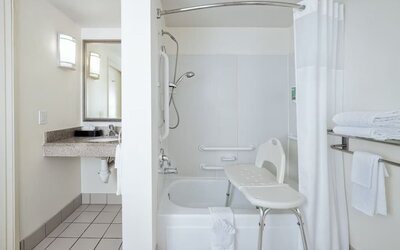 Accessible bathroom with bathtub, shower seat, grab bars, vanity, and mirror at Best Western Ontario Mills Mall.