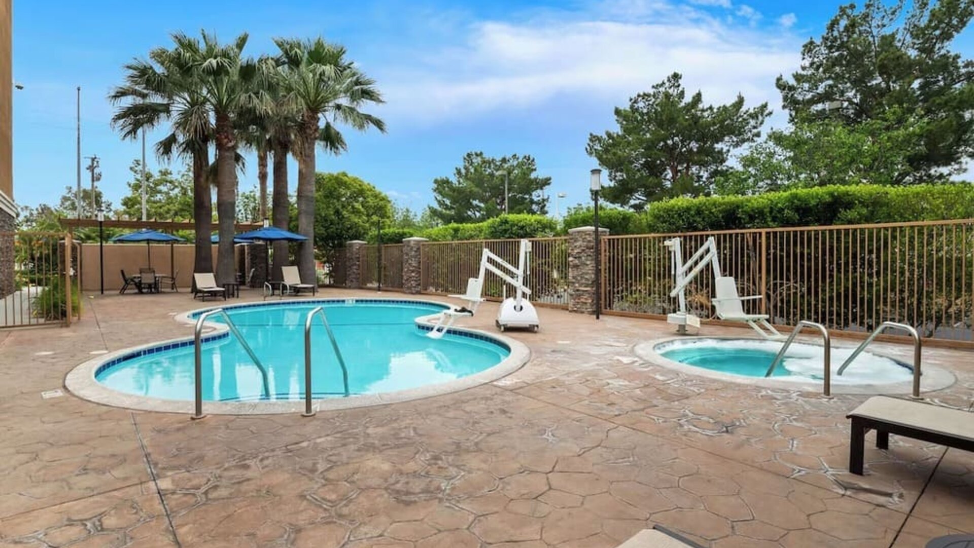 Outdoor swimming pool and hot tub surrounded by lounge seating and palm trees at Best Western Ontario Mills Mall.