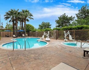 Outdoor swimming pool and hot tub surrounded by lounge seating and palm trees at Best Western Ontario Mills Mall.