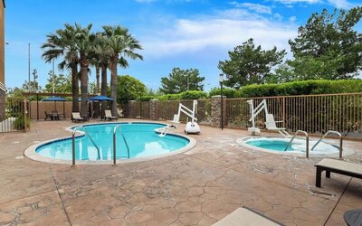 Outdoor swimming pool and hot tub surrounded by lounge seating and palm trees at Best Western Ontario Mills Mall.