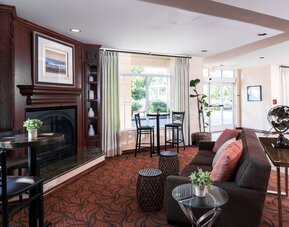 Lobby lounge with fireplace, sofa seating, high-top tables, and decorative furnishings at Best Western Ontario Mills Mall.