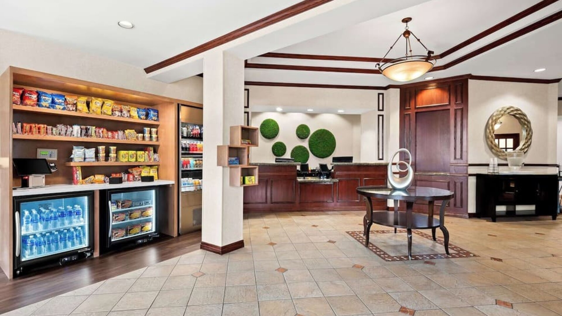 Reception area with front desk, marketplace stocked with snacks and drinks, and tiled flooring at Best Western Ontario Mills Mall.