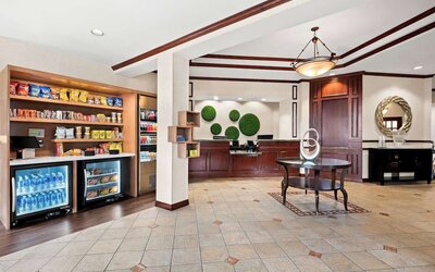 Reception area with front desk, marketplace stocked with snacks and drinks, and tiled flooring at Best Western Ontario Mills Mall.