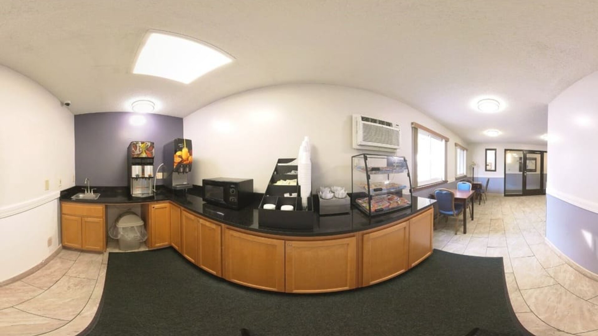 Breakfast area with beverage dispensers, microwave, pastry display, and dining tables at Coratel Inn & Suites By Jasper Hastings.