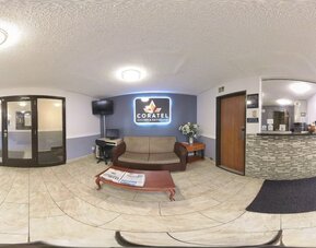 Reception and lobby area with front desk, sofa seating, coffee table, television, and business workstation at Coratel Inn & Suites By Jasper Hastings.
