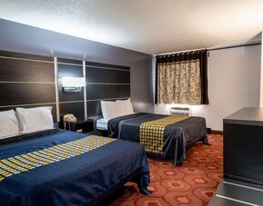 Guest room with two beds, patterned bedding, window, and dark wood furnishings at Coratel Inn & Suites By Jasper Hastings.