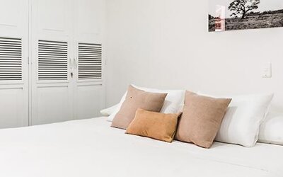 Guest room with large bed, neutral cushions, white wardrobes, and minimalist décor at Múcura Hotel & Spa.