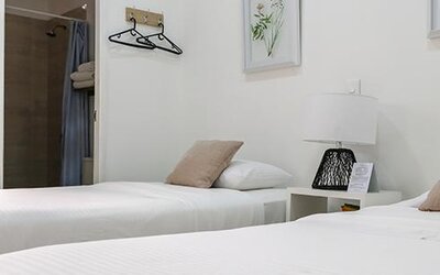 Guest room with two single beds, neutral décor, bedside lamp, and open bathroom area at Múcura Hotel & Spa.