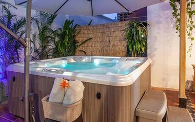 Outdoor hot tub surrounded by tropical plants, seating, and ambient lighting at Múcura Hotel & Spa.