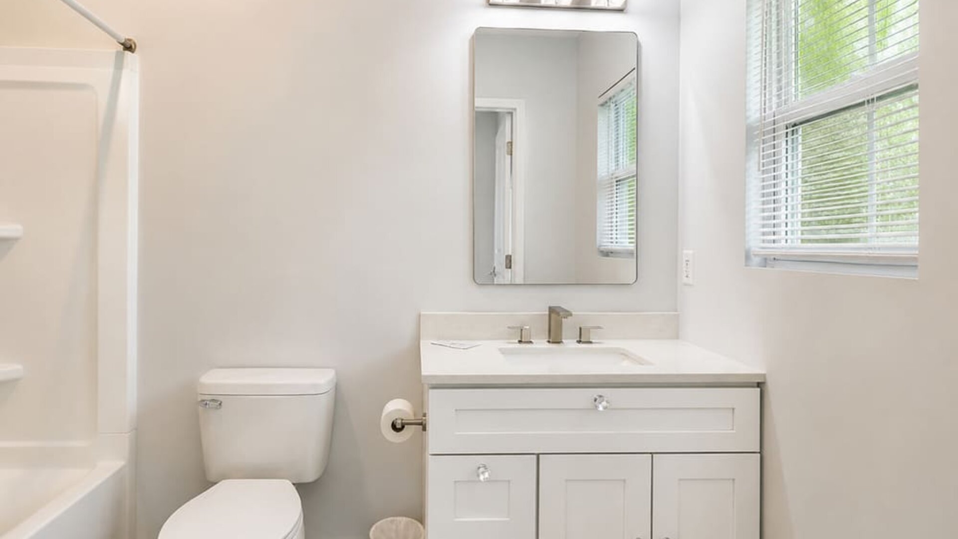 Bright guest bathroom featuring a vanity, mirror, toilet, window, and bathtub at SKYLARANNA Resort & Spa.