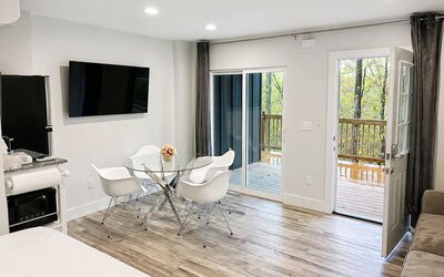Bright guest accommodation featuring a dining area, wall-mounted TV, kitchenette, and direct access to an outdoor balcony at SKYLARANNA Resort & Spa.