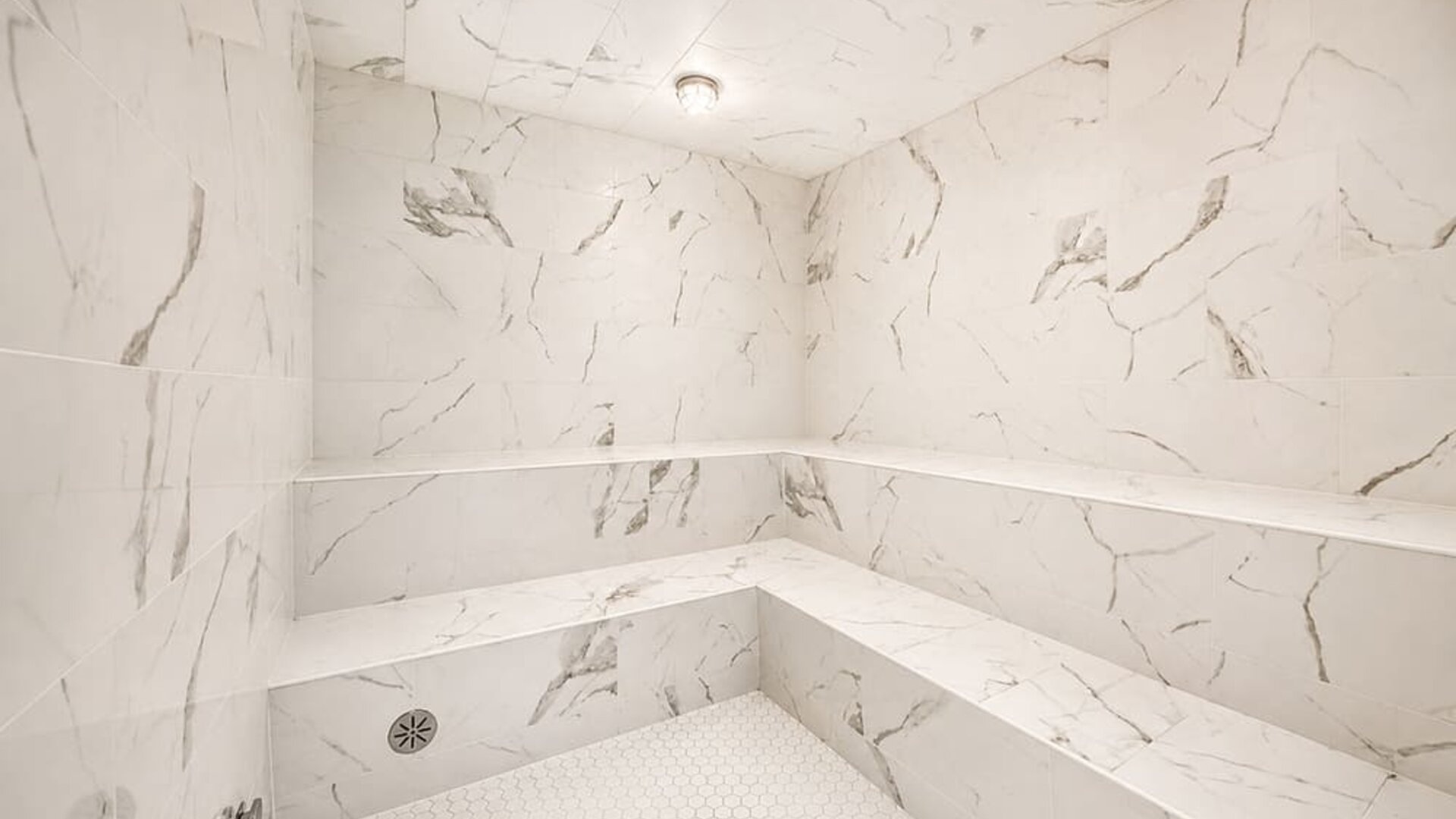 Steam room featuring marble-effect walls, built-in bench seating, and a bright contemporary interior at SKYLARANNA Resort & Spa.