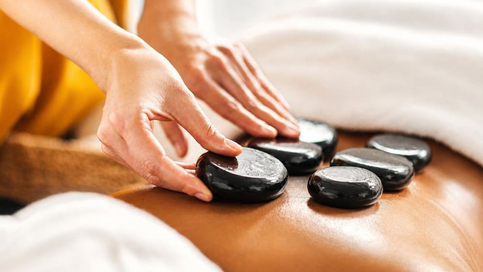 Hot stone massage treatment featuring heated stones placed along a guest's back at SKYLARANNA Resort & Spa.