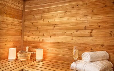 Wood-panelled sauna featuring bench seating, fresh towels, sauna accessories, and ambient lighting at SKYLARANNA Resort & Spa.