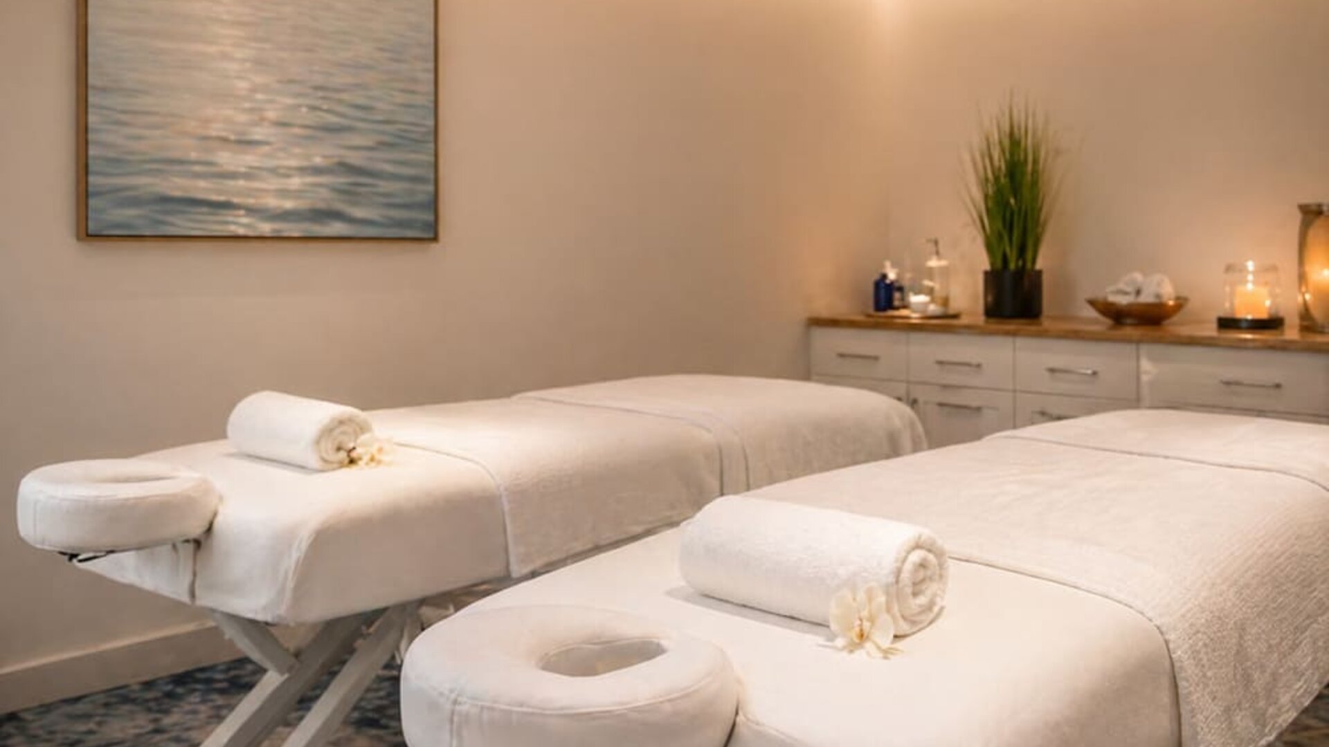 Spa treatment room featuring two massage tables, fresh towels, soft lighting, and contemporary décor at SKYLARANNA Resort & Spa.