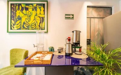 Guest refreshment station featuring coffee-making facilities, drinking water, snacks, and colourful artwork at Casa Anzures Suites.