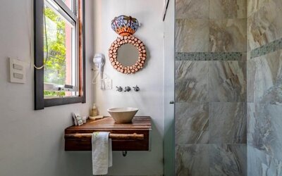 Guest bathroom featuring a vessel sink, wooden vanity, decorative mirror, natural light, and a tiled walk-in shower at Casa Anzures Suites.