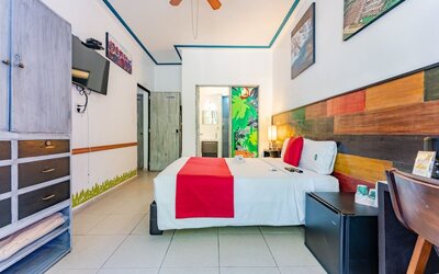 Spacious guest room featuring a large bed, colourful wood-panelled headboard, television, storage, and a desk at Casa Anzures Suites.