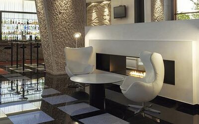 Stylish lounge area featuring contemporary white seating, a modern fireplace, and easy access to the hotel bar at Hilton Madrid Aeropuerto.