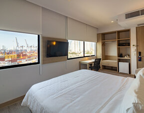 Bright guest room featuring a large bed, television, workspace, storage area, and views of the port at Holiday Inn Express Cartagena Manga.
