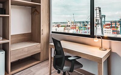 In-room workspace featuring a desk, ergonomic chair, coffee station, mini-fridge, and large window overlooking the port at Holiday Inn Express Cartagena Manga.