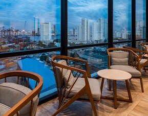 Comfortable lounge seating beside floor-to-ceiling windows overlooking the city and port at Holiday Inn Express Cartagena Manga.