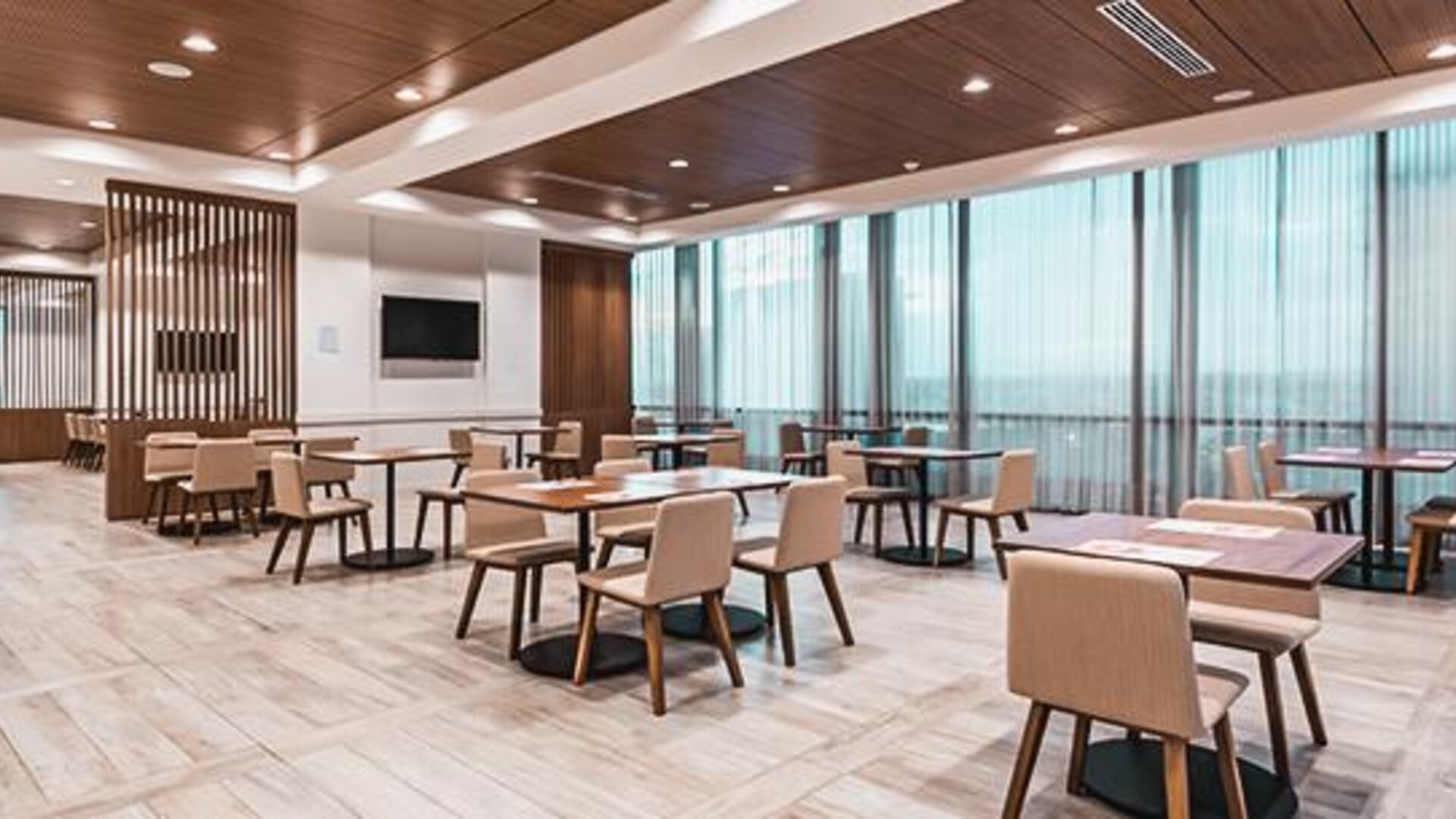 Bright dining area featuring contemporary seating, wood accents, and floor-to-ceiling windows at Holiday Inn Express Cartagena Manga.