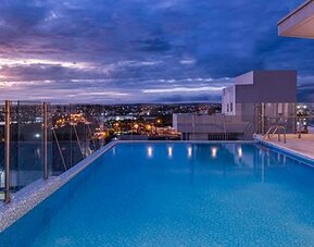 Rooftop outdoor swimming pool featuring panoramic city views and poolside loungers at sunset at Holiday Inn Express Cartagena Manga.