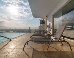 Rooftop pool deck featuring sun loungers, glass railings, and expansive views at Holiday Inn Express Cartagena Manga.