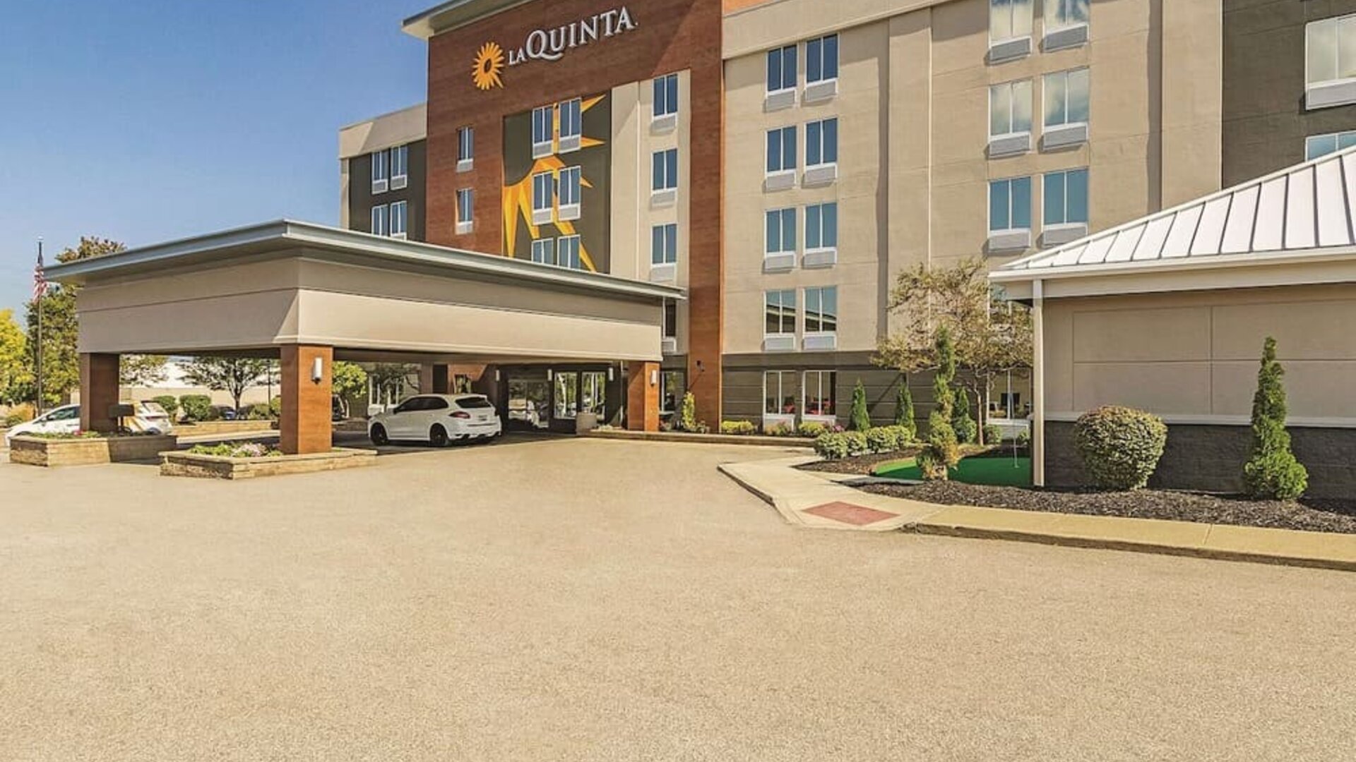 Exterior view of La Quinta Inn & Suites By Wyndham Cleveland Airport West featuring the hotel entrance, covered drop-off area, and landscaped surroundings.