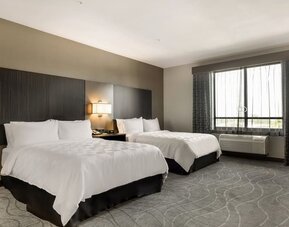 Spacious guest room featuring two beds, bedside lighting, a large window, and comfortable contemporary furnishings at Holiday Inn & Suites Silicon Valley - Milpitas.