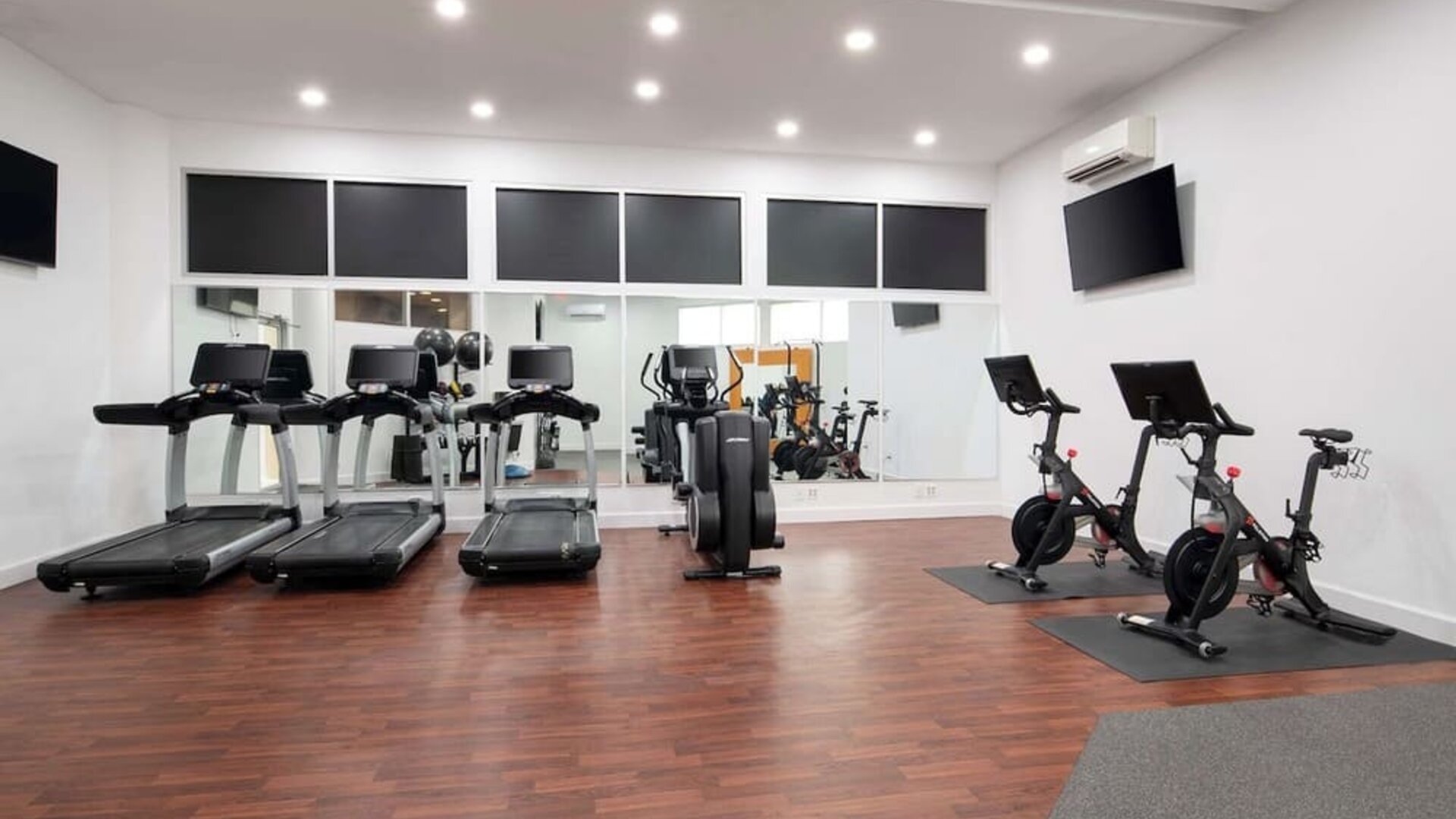Modern fitness centre featuring treadmills, stationary bikes, cardio equipment, and wall-mounted televisions at Embassy Suites by Hilton Crystal City National Airport.