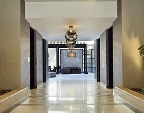 Contemporary hotel corridor and lobby area featuring decorative lighting, indoor greenery, and modern design at Embassy Suites by Hilton Crystal City National Airport.