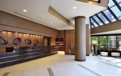Modern reception area featuring a spacious front desk, contemporary décor, seating, and abundant natural light at Embassy Suites by Hilton Crystal City National Airport.
