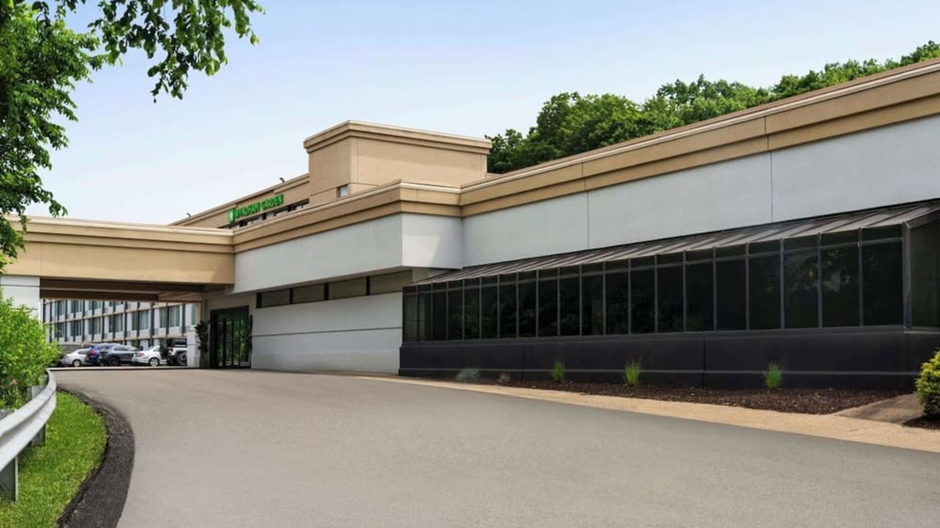 Exterior view of Wyndham Garden Pittsburgh Airport featuring the hotel entrance, covered driveway, landscaped grounds, and surrounding trees.