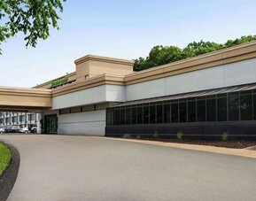 Exterior view of Wyndham Garden Pittsburgh Airport featuring the hotel entrance, covered driveway, landscaped grounds, and surrounding trees.