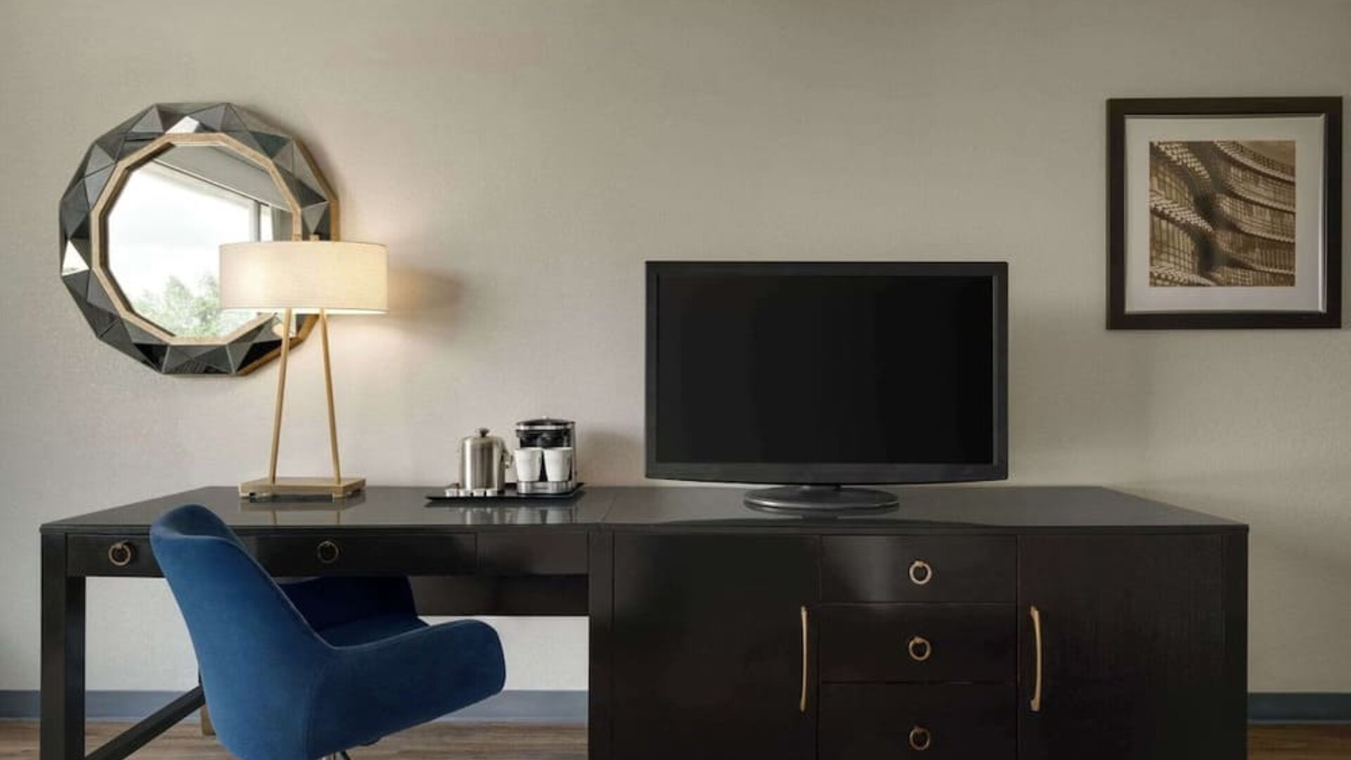 In-room workspace featuring a large desk, ergonomic chair, television, coffee station, mirror, and desk lamp at Wyndham Garden Pittsburgh Airport.