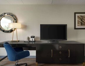 In-room workspace featuring a large desk, ergonomic chair, television, coffee station, mirror, and desk lamp at Wyndham Garden Pittsburgh Airport.